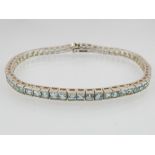 An aquamarine line bracelet in silver with princess cut stones. Length 20.5cm. Gross weight 11.9g.