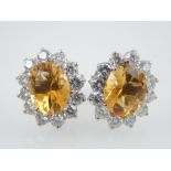 A pair of diamond and citrine cluster earrings in white gold, the central claw set oval cut stone,