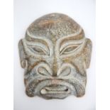 A large carved boulder jade Chinese mask, the stylised features set in a theatrical grimace, the