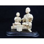 Early 20th C Japanese carved ivory figures, a father and son preparing fruit for their grass weave