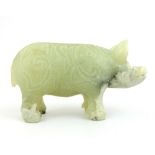 A Ching style celadon jade carved boar with all over relief and incised symbols, 7 x 14cm.