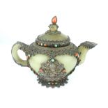 An antique Sino-Tibetan white metal mounted jade teapot, studded with cabouchon coral and other