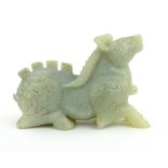 A Chinese carved all round green/grey jade figure of a crouching antelope with notched spine and