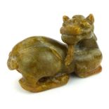 A Ming style carved olive green jade crouching mythical beast with beard and curling mane, 8 x