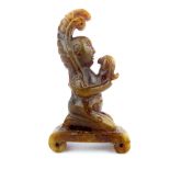 A Chinese small carved brown and green jade kneeling figure holding a bird, 8cm high.