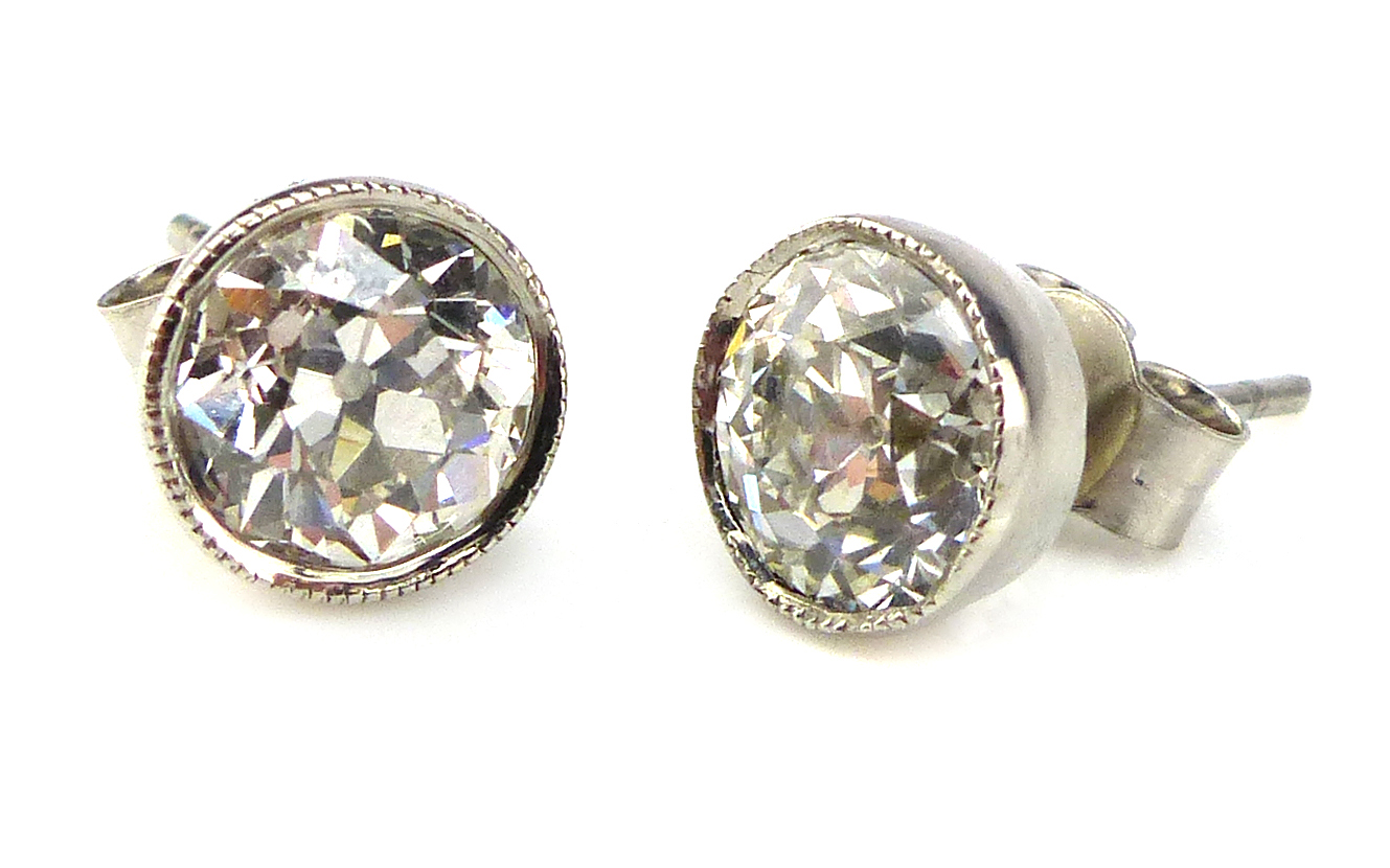 A pair of antique solitaire diamond stud earrings the round,