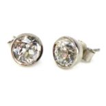 A pair of antique solitaire diamond stud earrings the round,