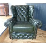 Dark green leather club chair of Chesterfield style, button back with brass stud trim.