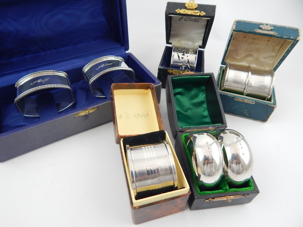 Eight cased silver napkin rings, George V and later, includes three pairs,