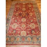 Kazak carpet, scrolling foliate design over red ground within flowerhead cream and blue borders,