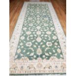 Turkish olive ground carpet, decorated with floral design within cream border, 422cm l,