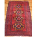 Persian red ground rug, decorated to centre with four geometric medallions,