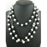 A string of alternate black glass and imitation white pearl necklace with silver CC design clasp