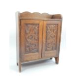 Welsh oak cabinet, two doors, the panels carved with caryatid dragons biting fish, c 1920,