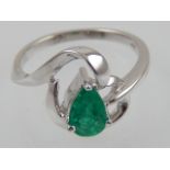 An 18ct white gold and emerald cross over cluster ring, the emerald of approx 0.