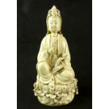 Cream glazed figure of guanyin, seated on a lotus blossom holding a ruyi sceptre,