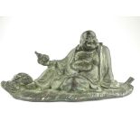 Bronze figure of Buddha, reclining of a leaf with an overflowing sack of food at his feet,