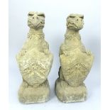 Pair of composite granite garden statues, gryphons with heraldic shields,