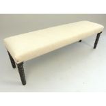 Upholstered window seat, the rectangular seat on ebonised bobbin turned legs,