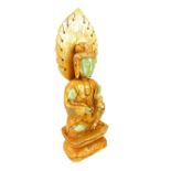 A gilded jade carving of Buddha, hand raised holding a lotus flower, seated on a pedestal, 29.