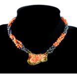 A coral and hematite necklace formed of three strands of beads, alternating coral,