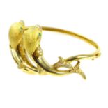 An unusual diamond and emerald dolphin bangle in yellow gold, the two modelled dolphins,