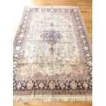 Kashmiri silk rug, the centre with tear drop medallion over floral and cream ground within indigo