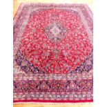 Large Keshan carpet, decorated with traditional floral design over red ground and indigo borders,