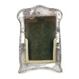 A George V silver photograph frame of shaped rectangular form,