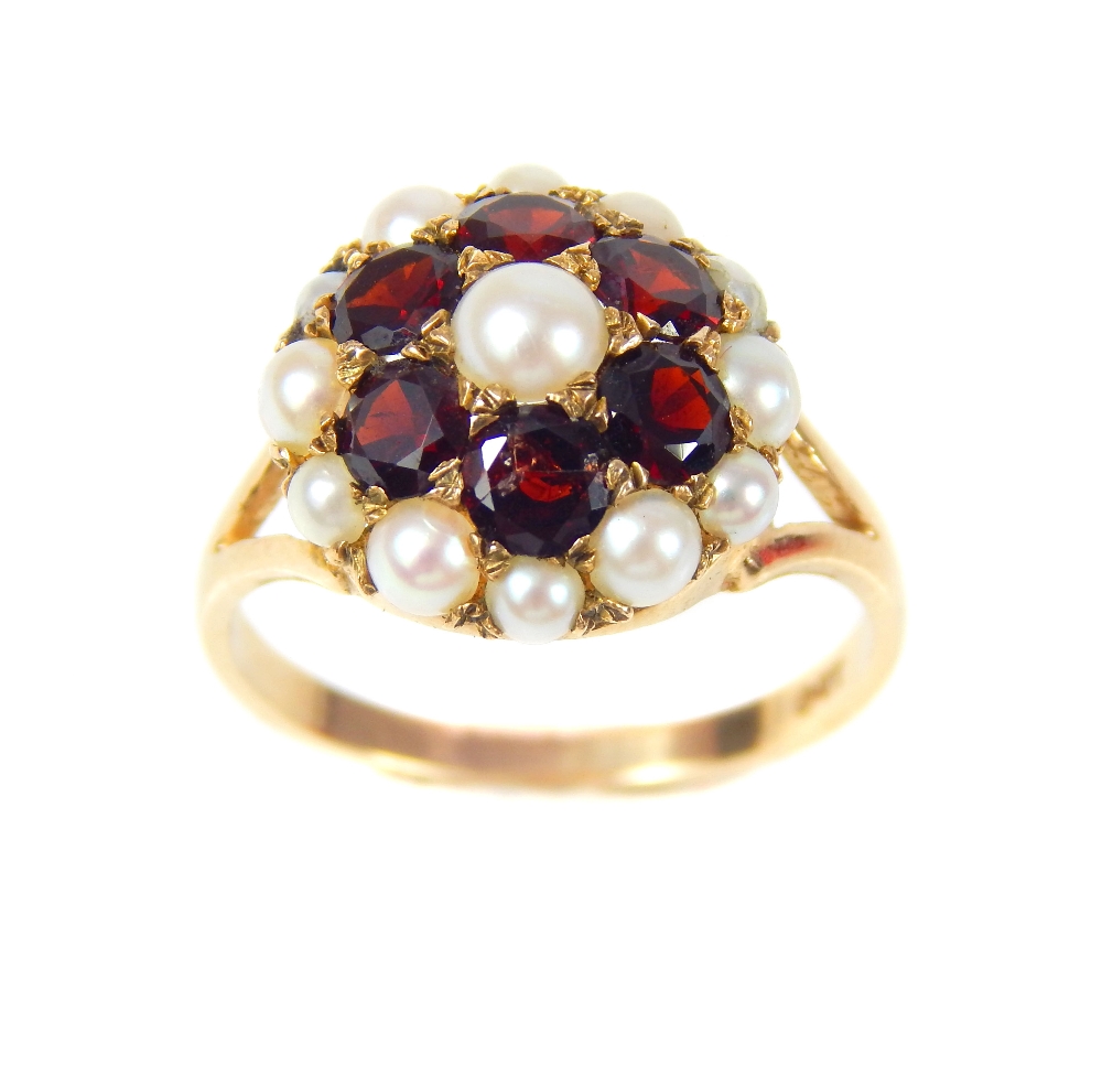 A 9ct yellow gold garnet and seed pearl flowerhead cluster ring, with pierced shoulders.