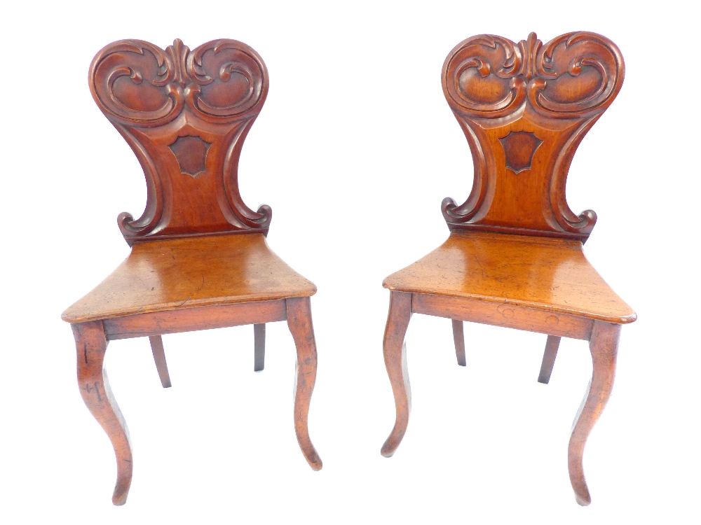A pair of William IV mahogany solid seat hall chairs with carved rococo shaped backs & vacant