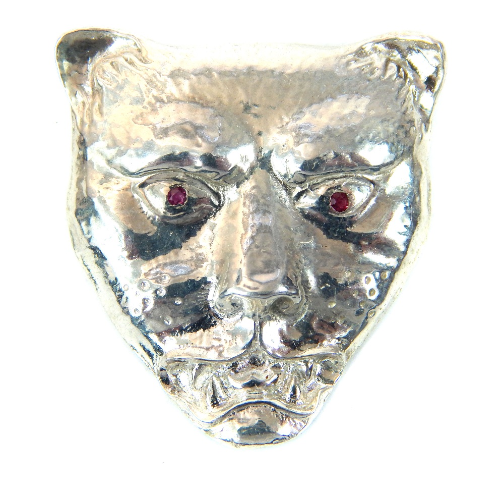 A silver pendant in the form of a leopards head, inset with ruby eyes, 3cm long