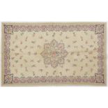 Tapis brodé- Inde- 2ème moitié du XXe s.- à médaillon central sur fond beige parsemé de fleurs-