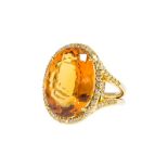 Bague en or 750 sertie d'une citrine taille ovale (env. 19 ct) entourée de diamants taille brillant-