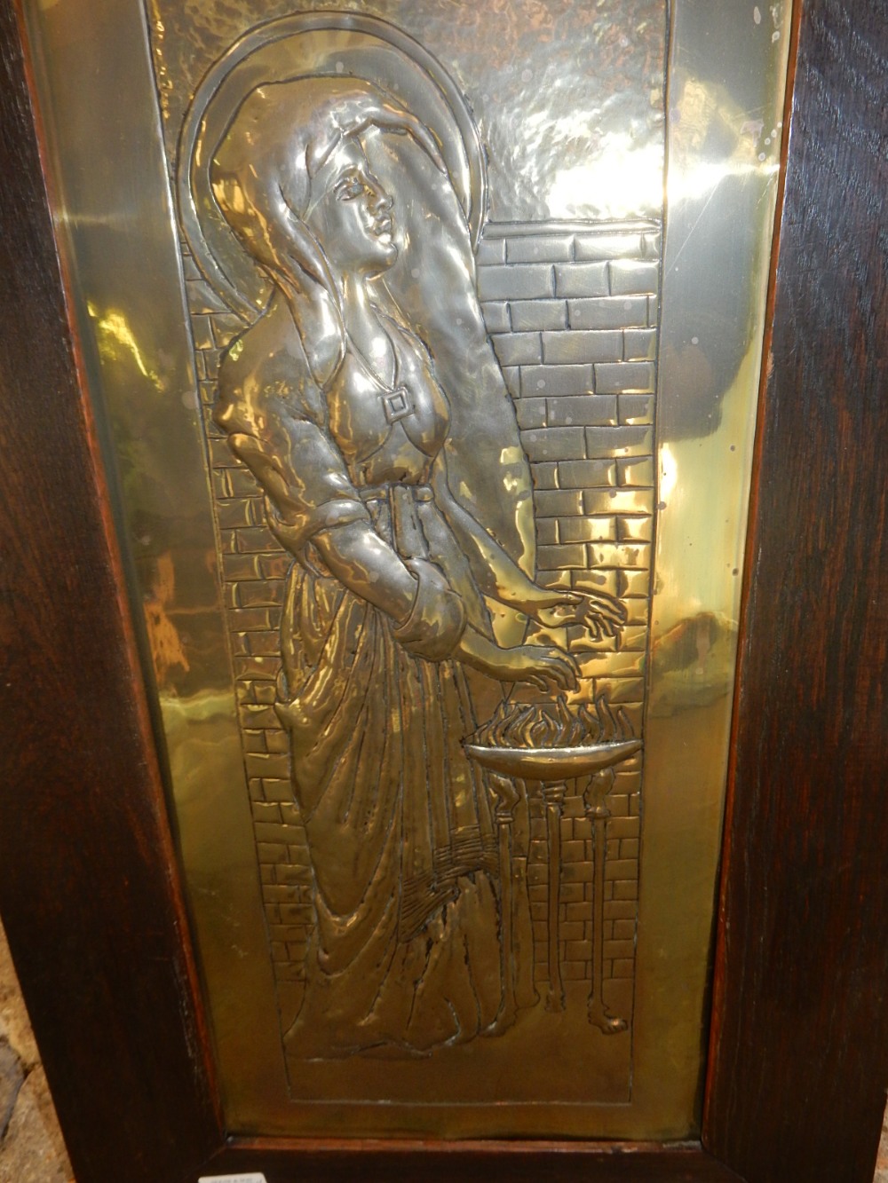 An Arts and Crafts repousse decorated brass panel depicting a pre-Raphaelite maiden initialled, in a