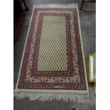 An Eastern rug, cream with red, blue and green stylised decoration, fringed