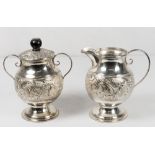 An Eastern silver coloured metal jug and matching double handled sucrier with raised decoration of