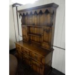 An oak dresser, the raised back fitted shelves, the base fitted three frieze drawers, cupboards