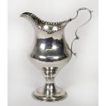 A George III silver cream jug with serrated rim, shaped handle, on circular base - London 1785