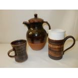 A Winchcombe Pottery coffee pot, mugs and saucers, brown glazed and a set of three graduated jugs by