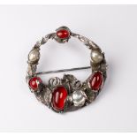 An Arts and Crafts style brooch set red cabochons and pearls, in a silver coloured metal frame in