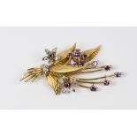 A gold coloured metal flower spray brooch set purple, blue and red stones with diamonds