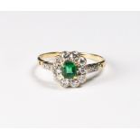 A lady's ring set centre emerald surrounded by diamonds, on a gold shank