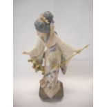 A Lladro figure of a Geisha girl holding a closed parasol - 11in. high