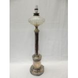 An oil lamp with clear reservoir, on a silver plated column, on circular base