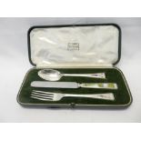 A child's Elkington and Co. silver three piece christening set with enamel decorated handles, in