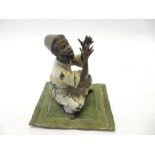 A cold painted bronze model of an Arab seated on an Eastern rug - 3 1/2in. high