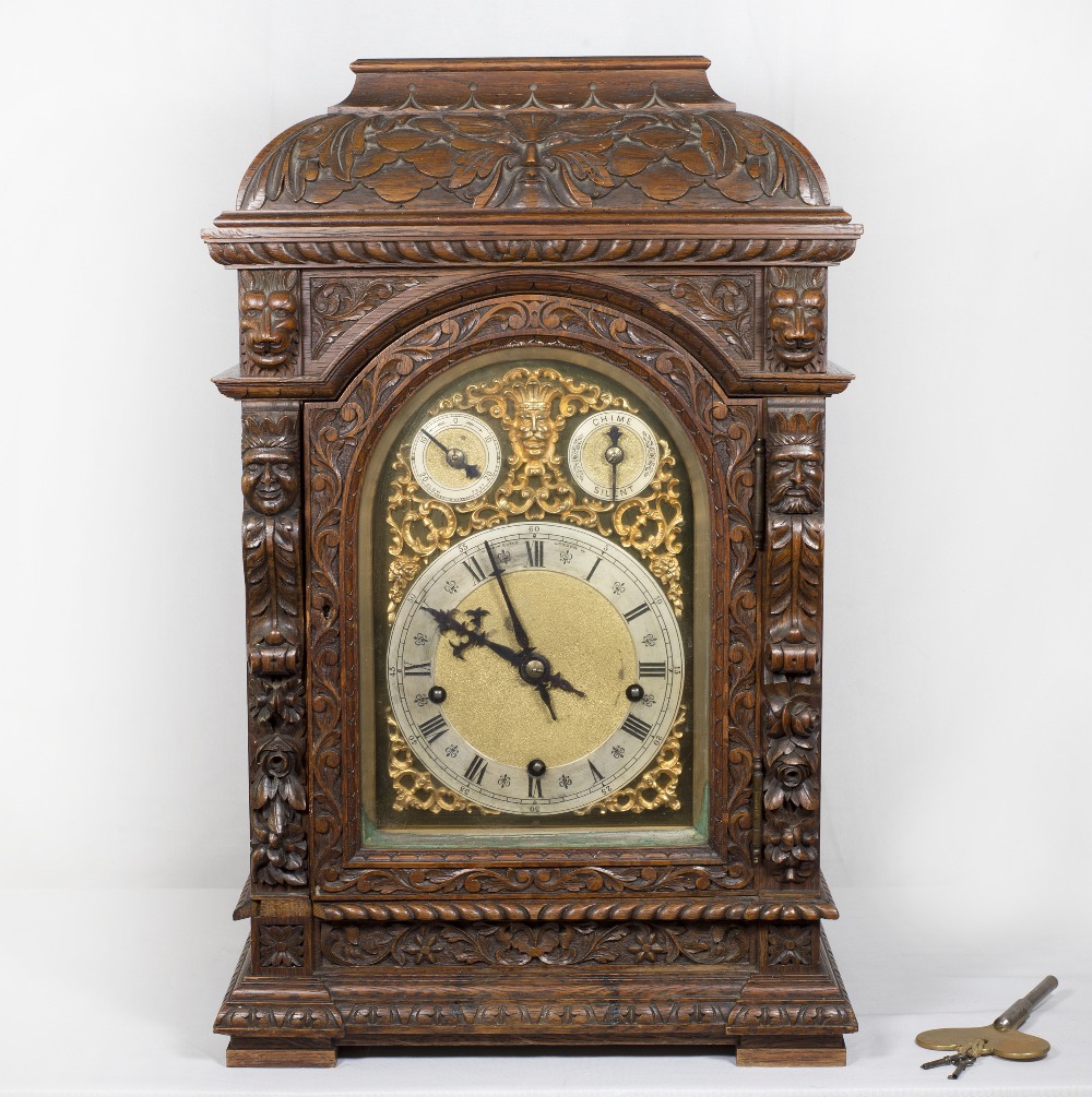 A Victorian bracket clock with arched brass dial pierced to mask design, silvered chapter ring,