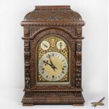 A Victorian bracket clock with arched brass dial pierced to mask design, silvered chapter ring,