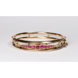 A 9ct. gold stiff hinged bangle, the top inset rubies